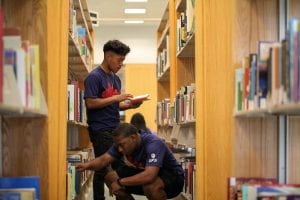 Two male students look through books in the IUPUI library.