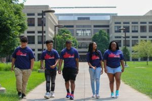 Five Upward Bound students walk through campus together, laughing.