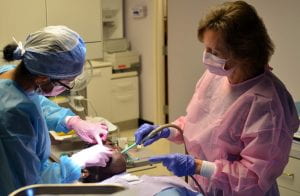 A dentist and assistant lean over a patient during a dental procedure.