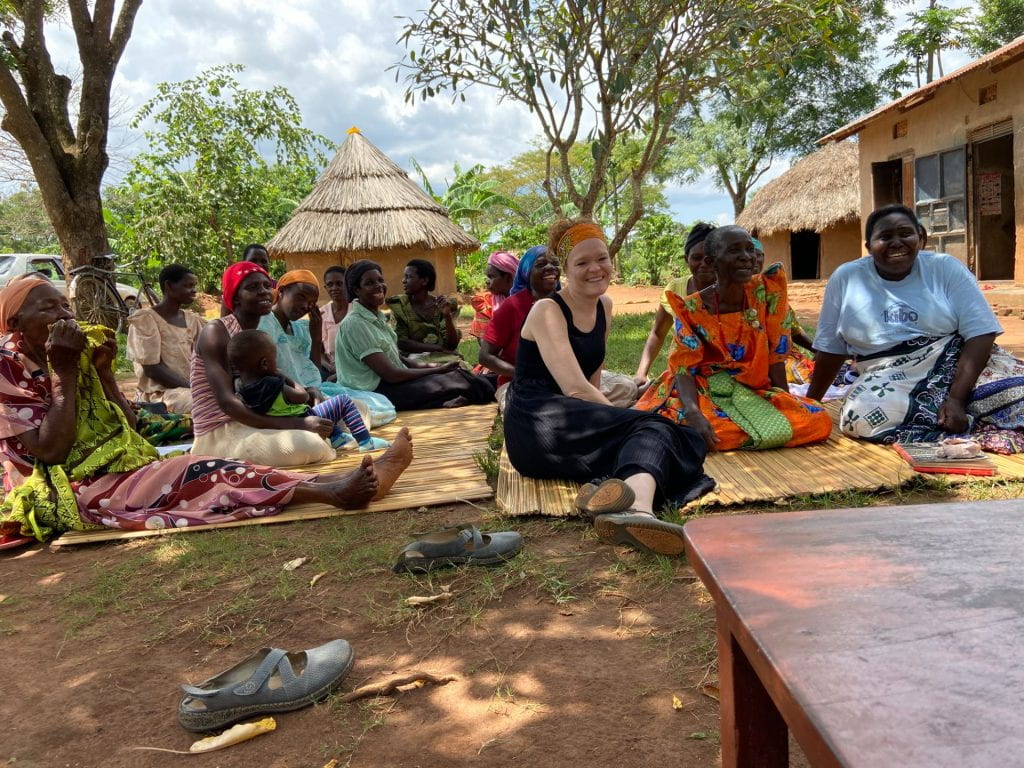 Danny Cagnet sits on straw mats with several members of the village.