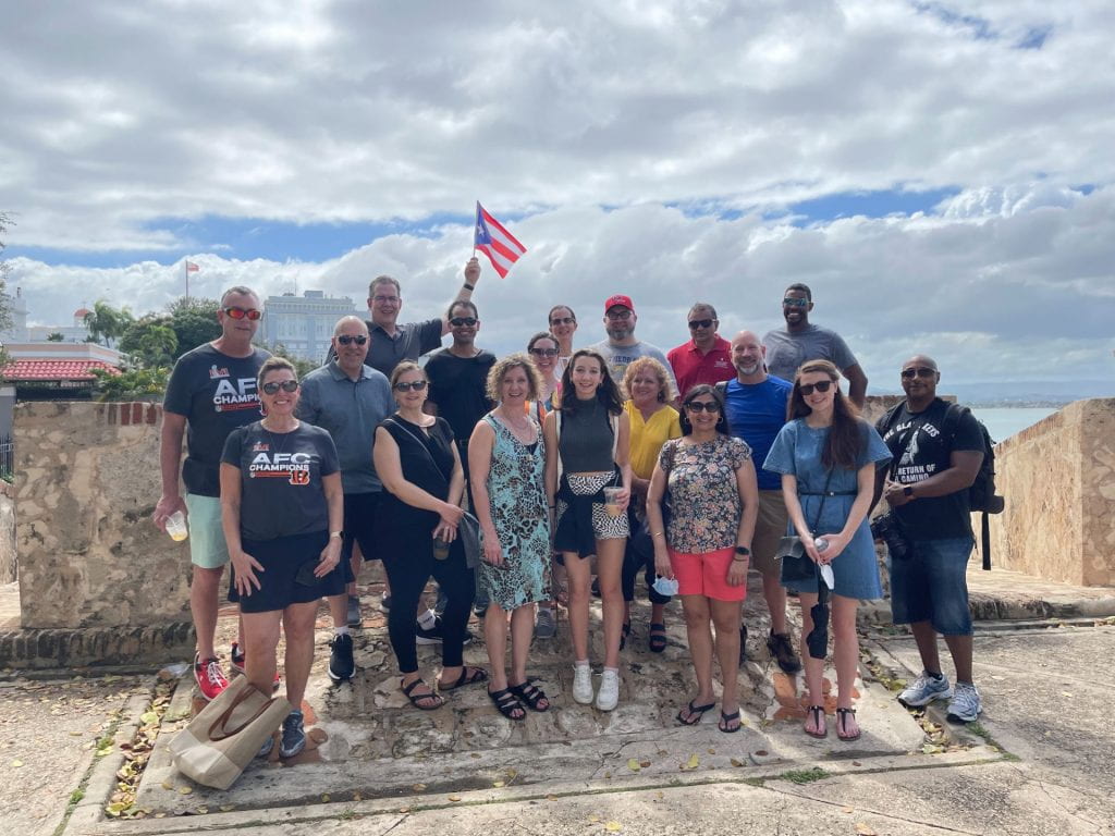 A group of Physician MBA students, faculty, and staff pose with the Puerto Rican flag during the Global Healthcare Experience course.