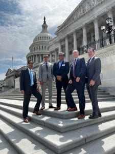 Five physicians in suit stand on the steps near the U.S. Capitol.