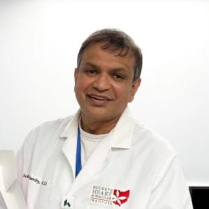 Dr. Sukir Sinnathamby in a white coat.