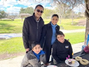 Dr. Pawar stands at a park table with her husband and two young sons.